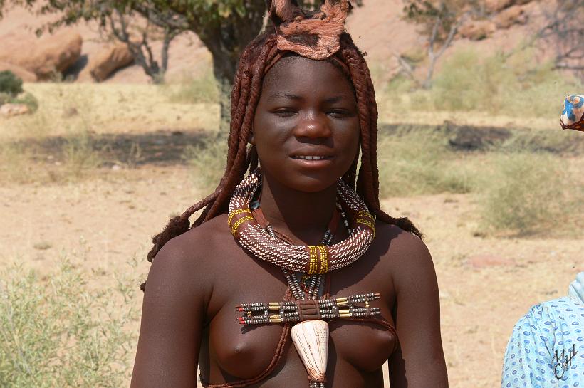 P1140005.JPG - Jeune fille de l'ethnie Himba. Ils sont env. 10.000 à vivre dans la région du Kaokoland. Ils se teignent la peau et les cheveux en rouge avec une pommade réalisée à base de graisse animale et de poudre d'hématite (pierre rouge) afin de se protéger du soleil, de la sécheresse de l'air et des insectes.