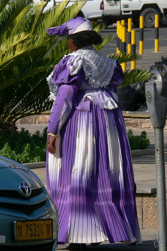 P1150448.JPG - Les femmes Herero portent encore aujourd'hui une robe longue sous une panoplie de jupons et une coiffe avec deux cornes pointues. Cette tenue date de l'époque victorienne et des missionnaires allemands. Ici au centre ville de Windhoek.