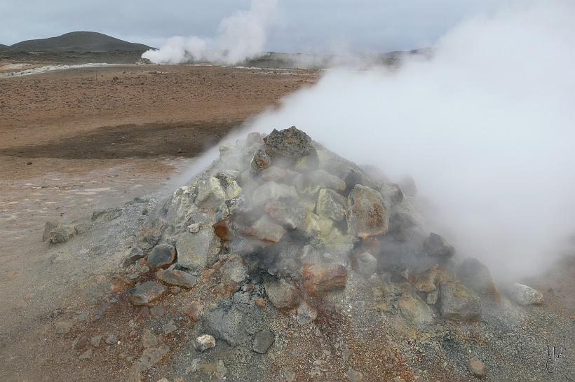 060731_Islande_SiteGeothermiqueHverarond_392.JPG - Des jets de vapeur sulfatés s’échappent et colorent les roches et la montagne en jaune ocre et orange.